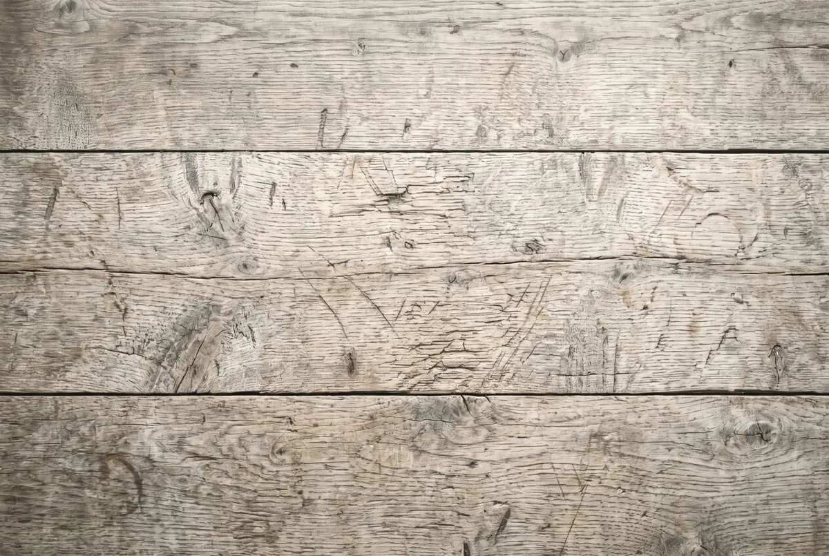 The surface of an old wooden work table seen from above, wide boards marked by years of use